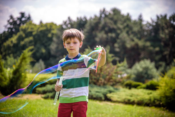 niño jugando con su juguete de burbujas de jabón en el parque. actividad infantil. concepto primaveral - child dancing preschooler outdoors fotografías e imágenes de stock