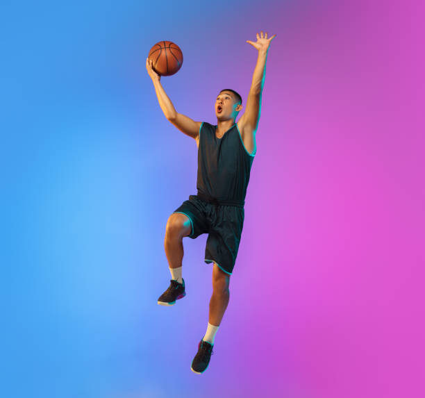 istock Young basketball player in motion on gradient studio background in neon light 1263433989