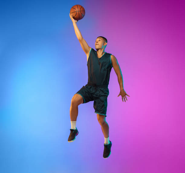istock Young basketball player in motion on gradient studio background in neon light 1263433990