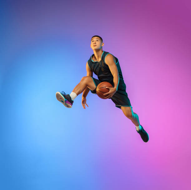 istock Young basketball player in motion on gradient studio background in neon light 1263433991