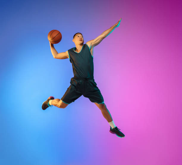 istock Young basketball player in motion on gradient studio background in neon light 1263433994