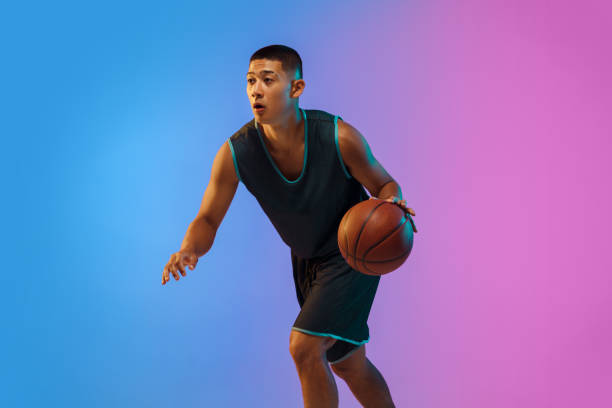 istock Young basketball player in motion on gradient studio background in neon light 1263433995