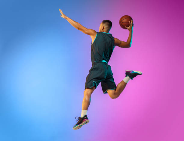 istock Young basketball player in motion on gradient studio background in neon light 1263433996