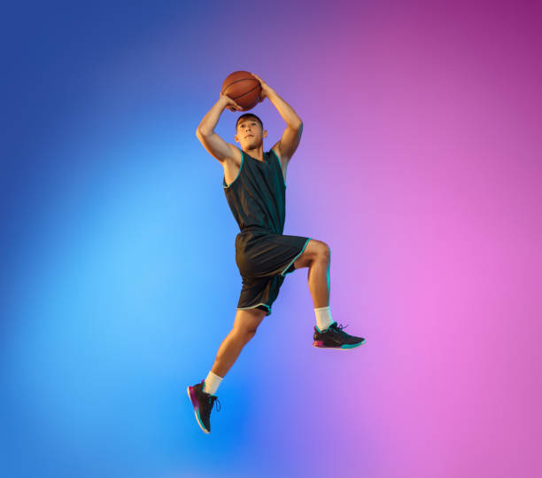 istock Young basketball player in motion on gradient studio background in neon light 1263433998