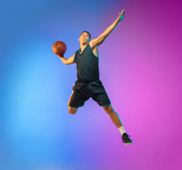 istock Young basketball player in motion on gradient studio background in neon light 1263434001