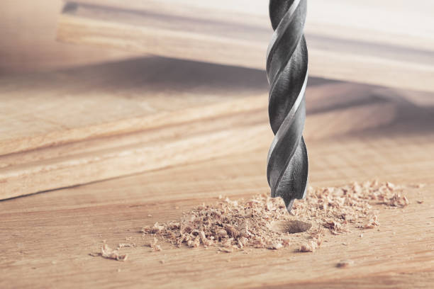 istock drill makes a hole in the wooden oak table with wood 1263434613