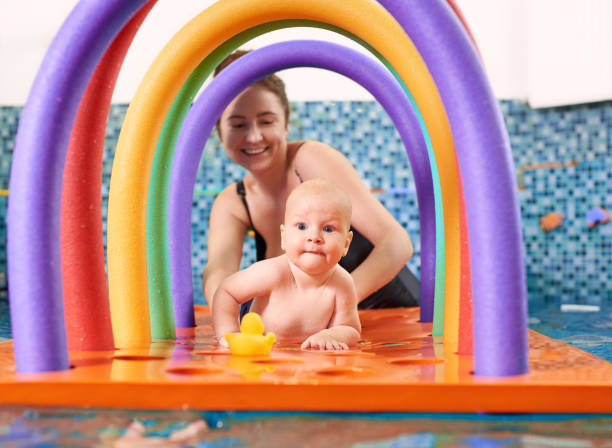 cours de natation pour les petits, bébé avec la mère dans la piscine pendant l’entraînement - floating on water water women wet photos et images de collection
