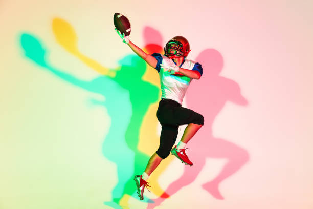 American football player isolated on gradient studio background in neon light with shadows