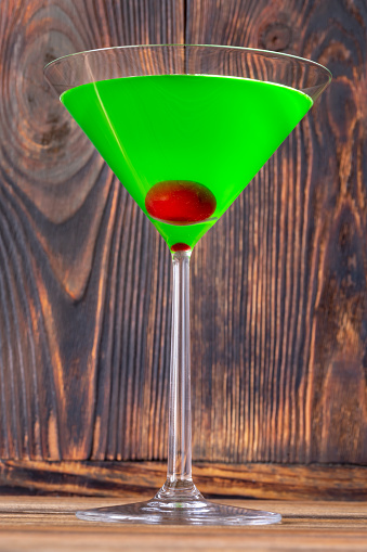 Glass of Japanese Slipper Cocktail on wooden background