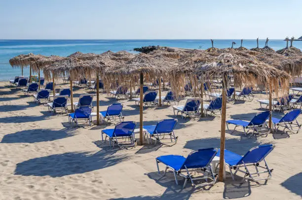 Straw beach umbrellas and sun chairs on the east coast of Zakynthos island in Greece