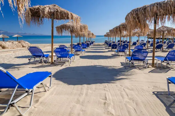 Straw beach umbrellas and sun chairs on the east coast of Zakynthos island in Greece