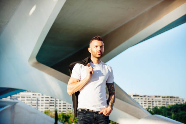 istock young man with jacket on shoulder and short beard walking 1263441942