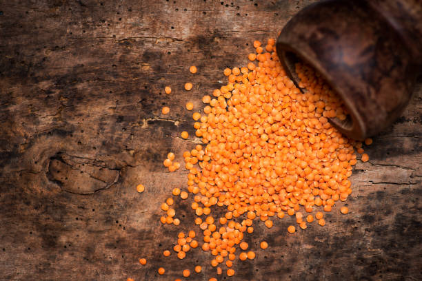 red lentil grains in a rustic bowl on a wooden table - falling beans imagens e fotografias de stock