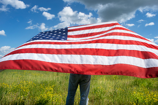 Man holding American flag waving in the wind, freedom, independence, liberty