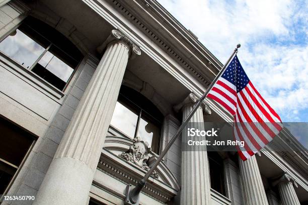 American Flag Flying Over Government Building In City Blue Sky And Clouds Stock Photo - Download Image Now