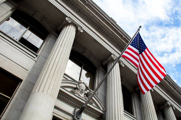 american flag flying over government building in city, blue sky and clouds - político imagens e fotografias de stock