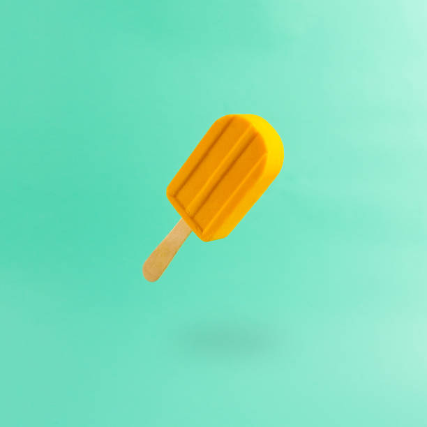 Yellow popsicle floating against abstrcat mint green background with copy area.