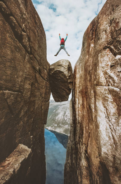 brave man jumping over kjeragbolten extreme travel in norway kjerag mountains summer vacations adventure success concept - rock norway courage mountain imagens e fotografias de stock