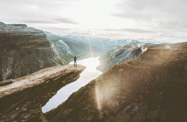Man on Trolltunga cliff edge happy raised hands traveling in Norway adventure lifestyle extreme vacations outdoor sunset mountains landscape aerial view Man on Trolltunga cliff edge happy raised hands traveling in Norway adventure lifestyle extreme vacations outdoor sunset mountains landscape aerial view mountain climbing photos stock pictures, royalty-free photos & images