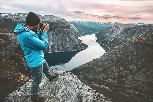Man travel photographer taking photo landscape in Norway mountains standing on cliff hobby lifestyle adventure vacations lake aerial view