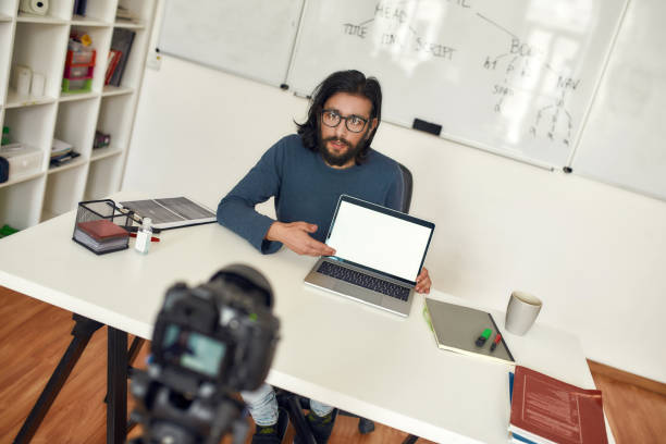 istock Programming tutor, male teacher pointing at laptop blank screen and explaining new theme, recording video tutorial on professional digital equipment 1263457320