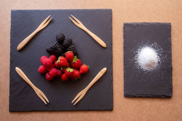 istock Forest fruits, raspberries, blackberries and strawberries in a rectangular plate on a brown and shaded base. With wooden forks and a slate plate. 1263462502