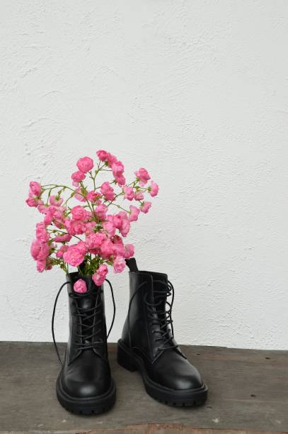 istock Pink roses in black leather boots 1263465443