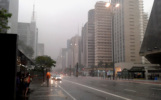 People take shelter from the torrential rain that falls on the iconic Paulista avenue during the summer in São Paulo, Brazil.