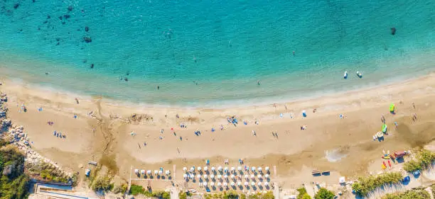 Photo of Aerial top view panorama of beautiful Coral beach in Paphos with azure seawater, Cyprus. Sand coast with umbrellas, sunbeds, people and clear sea water