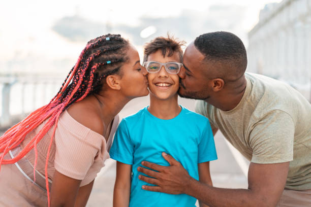 istock Parents kissing their son outdoors 1263468024