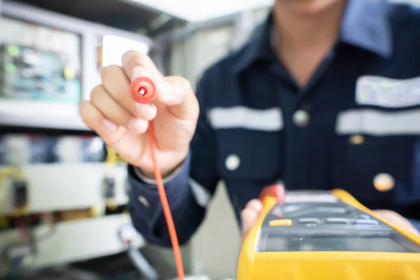 The positive end of the multimeter held by an engineer with a blurred background, the concept of using digital tools to check electrical and electronic equipment. Intentional blur image.