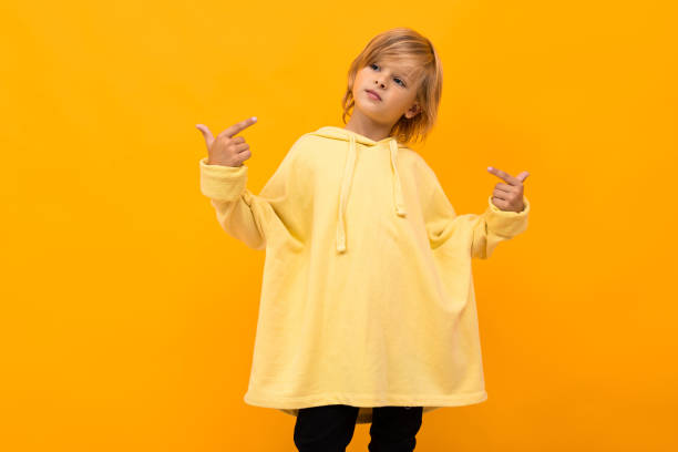 istock cool blond boy with a panama in a light hoodie with glasses posing on a yellow studio background 1263478047