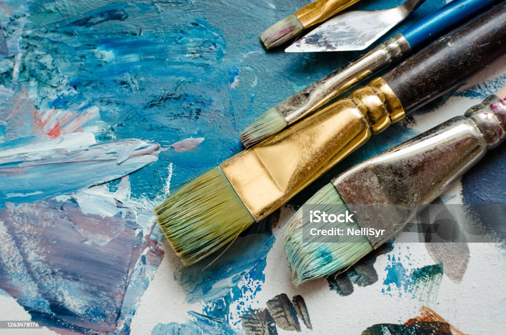 Artist paint brushes on the wooden palette Artist paint brushes on wooden palette. Texture mixed oil paints in different colors. Instruments tools for creative leisure. Painting hobby background. Paintings art concept. Top view. Copy space. Paintbrush Stock Photo