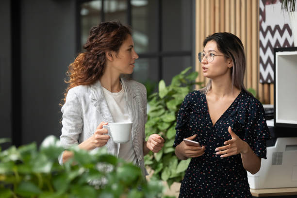 Diverse employees chatting during coffee break in modern office