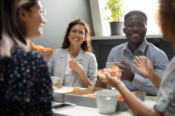 istock Happy diverse colleagues tasty eating pizza, chatting during lunch break 1263482592