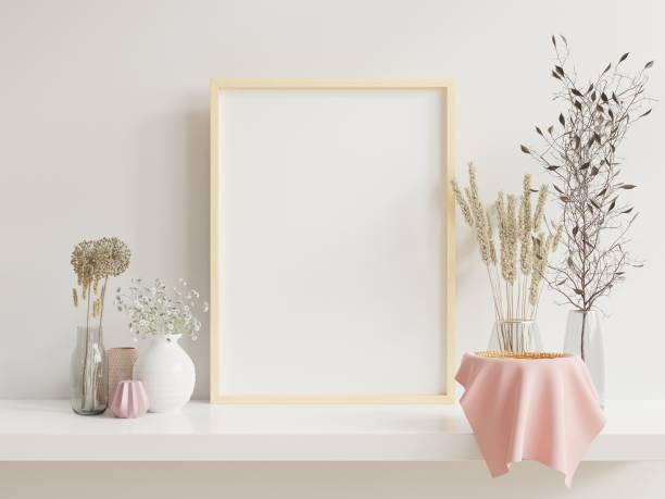 istock Wooden frame leaning on white shelf in bright interior with plants on the table with plants in pots on empty wall background. 1263494726