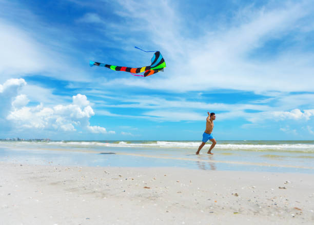 istock Young man flying a kite in an empty beach 1263496209