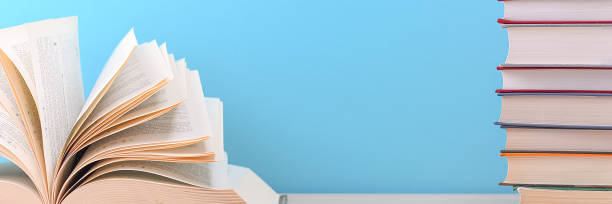 istock The book is open, the sheets are fan-shaped on a blue background next to a stack of books. 1263503883