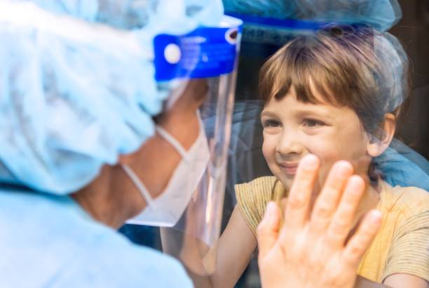 istock Mature Healthcare worker posing seeing her son with a window glass separating them to avoid possible contagion 1263514434
