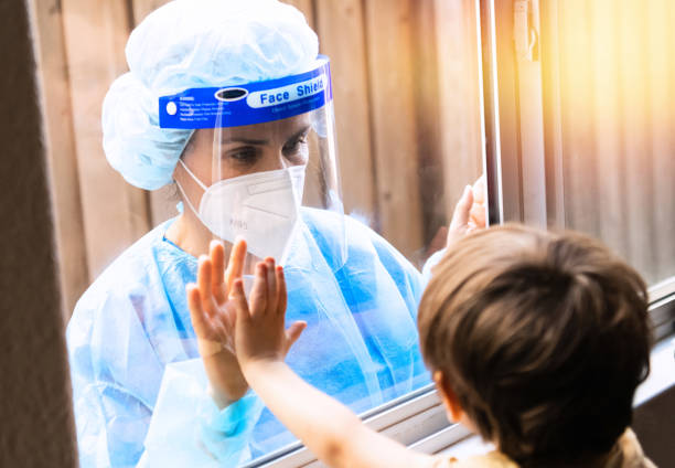 istock Mature Healthcare worker posing seeing her son with a window glass separating them to avoid possible contagion 1263515126