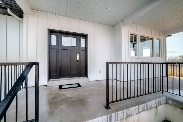 Home entrance with front porch and black front door against white panelled wall Home entrance with front porch and black front door against white panelled wall. Stairs leads to the entrance of this house with glass panes on the door. front porch stock pictures, royalty-free photos & images