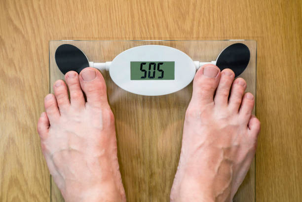계량 스케일에 대한 남자의 발. 체중 규모의 맞춤법 sos와 다이어트 문제 개념. sos를 보여주는 체중 규모에 서있는 사람. 다이어트 필요 - dieting overweight weight scale help 뉴스 사진 이미지