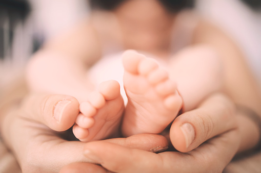 Feet of a newborn baby in the hands of parents.