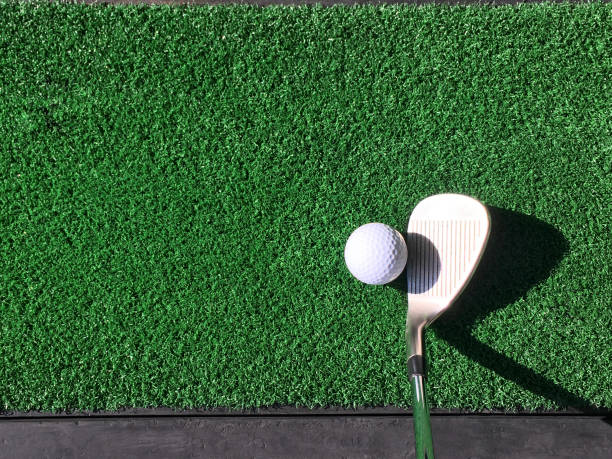 istock One white golf ball with wedge iron club on practice artificial grass mat under morning sunlight 1263533351