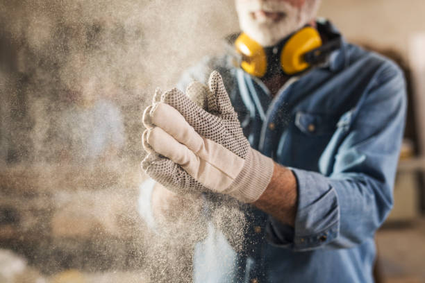 Carpenter cleaning work gloves Carpenter cleaning work gloves from sawdust after he finished processing the wood rolled up sleeves stock pictures, royalty-free photos & images