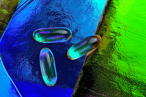 omega-3 capsule with vitamin on a colored background. view from above.