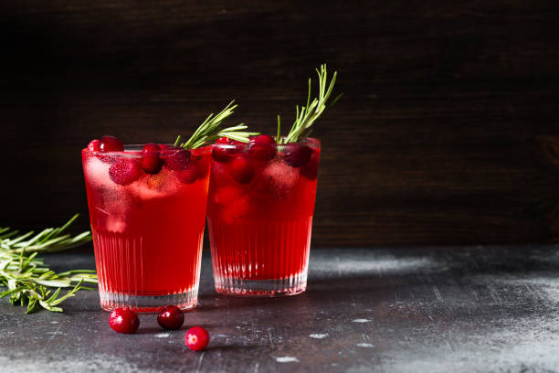 cocktail di bevande ai mirtilli rossi con ghiaccio e rosmarino su sfondo scuro - cranberry juice foto e immagini stock