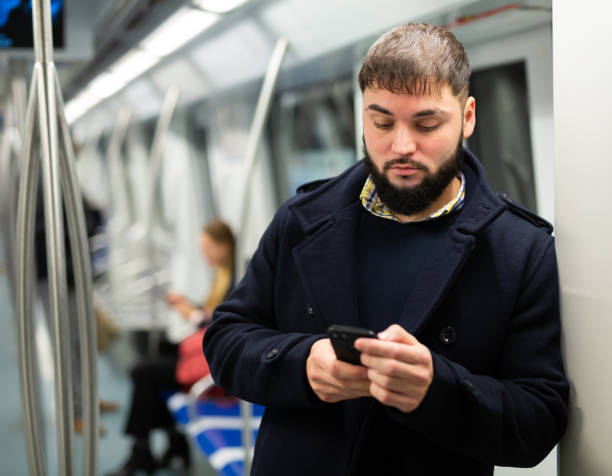 istock Young man with phone in subway car 1263540882
