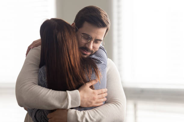 Handsome man embracing woman calms in difficult moment. Handsome man embracing woman calms in difficult moment. Husband hugging wife relieves stress from work or health. Friends and couple relationship concept. mercy hug stock pictures, royalty-free photos & images