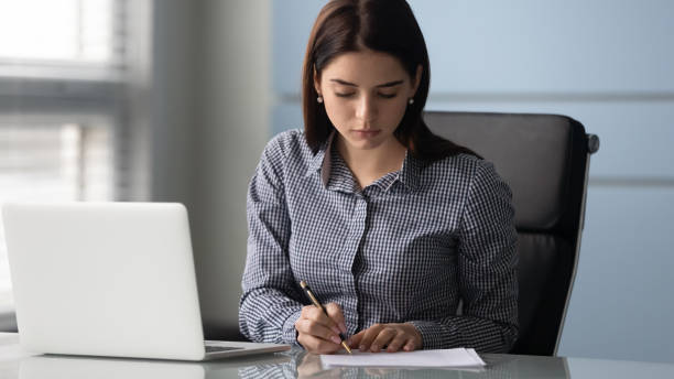 istock Young serious businesswoman sign up document at work. 1263543138